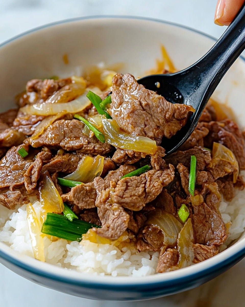 Gyudon Japanese Beef Rice Bowl, Japanese beef bowl recipe, easy Gyudon recipe, homemade Japanese rice bowl, savory Gyudon dish A white bowl with a blue rim filled with a bottom layer of plain white rice, topped with thin slices of cooked brown beef mixed with translucent cooked onions and green scallion pieces. A black spoon scoops some of the beef and onions from the bowl, held by a woman's hand on the right side of the image. The bowl is placed on a white marbled surface.