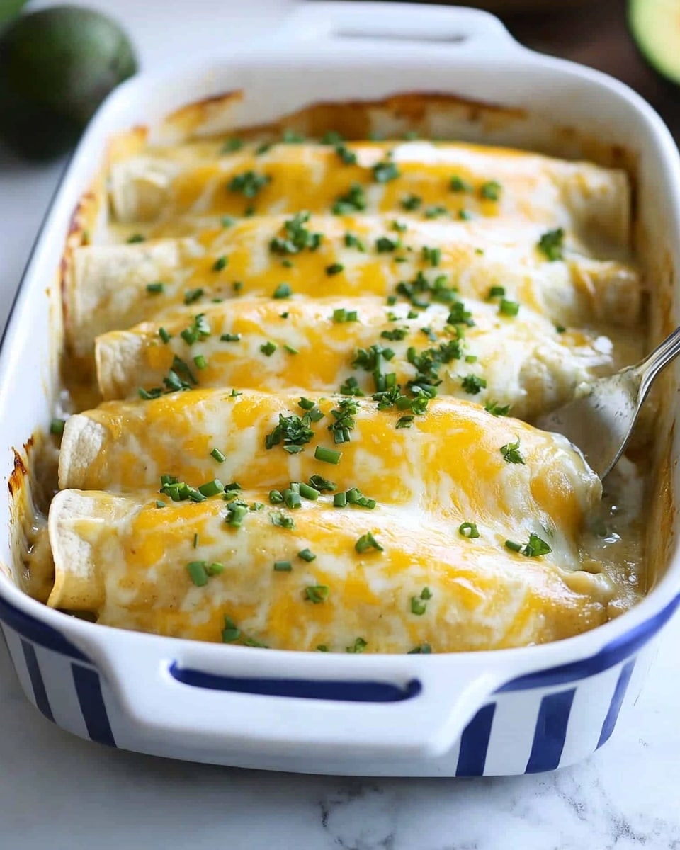A white baking dish with blue stripes holds four enchiladas, each covered with melted white and yellow cheese that drips slightly. The enchiladas have a golden-brown baked texture, topped with small bits of chopped green onions scattered evenly. A spatula lifts one enchilada in front, showing its soft, cheesy, and slightly crispy texture. In the blurred background, a wooden board holds halved avocados and some lime wedges on a white marbled surface. photo taken with an iphone --ar 4:5 --v 6.1