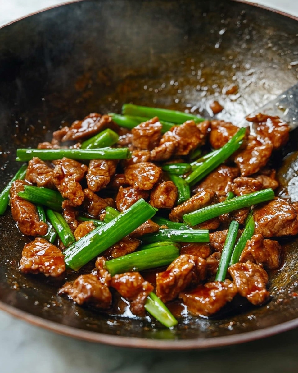 The image shows a large black wok with cooked pieces of reddish-brown meat covered in a shiny sauce, mixed with bright green chopped scallions spread evenly on top. The sauce glistens with a slightly thick texture, and the green scallions add a fresh, vibrant contrast. The wok sits on a stove, and a metal spatula is visible on the right side, lifting some of the food. The background surface is a white marbled texture. photo taken with an iphone --ar 4:5 --v 6.1