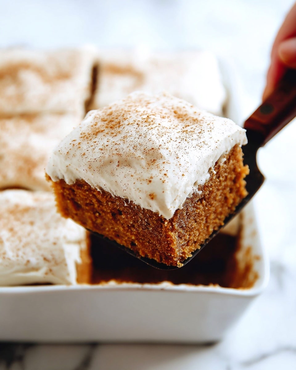 A close-up view of a single square piece of brown cake with a thick layer of smooth, creamy white frosting on top, sprinkled with light brown spice powder. The cake piece is held by a spatula with a wooden handle, lifted out from a larger batch of similar square cake pieces inside a white baking dish. The cake's texture looks soft and moist, and each piece has the same white frosting layer and spice sprinkle on top. The background is a white marbled texture. Photo taken with an iphone --ar 4:5 --v 7