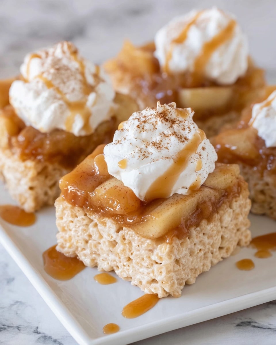 The image shows three square pieces of crispy, light golden rice treats arranged on a white plate with a white marbled background. Each square has a layer of glossy, amber-colored cooked apples on top, covered with a dollop of white whipped cream. A light dusting of cinnamon powder is sprinkled over the whipped cream, and a drizzle of sticky caramel sauce runs over the apples and the sides of the rice treats, creating a shiny texture. The focus is on the front piece, highlighting the smoothness of the whipped cream and the soft, caramelized apples beneath it. Photo taken with an iphone --ar 4:5 --v 7