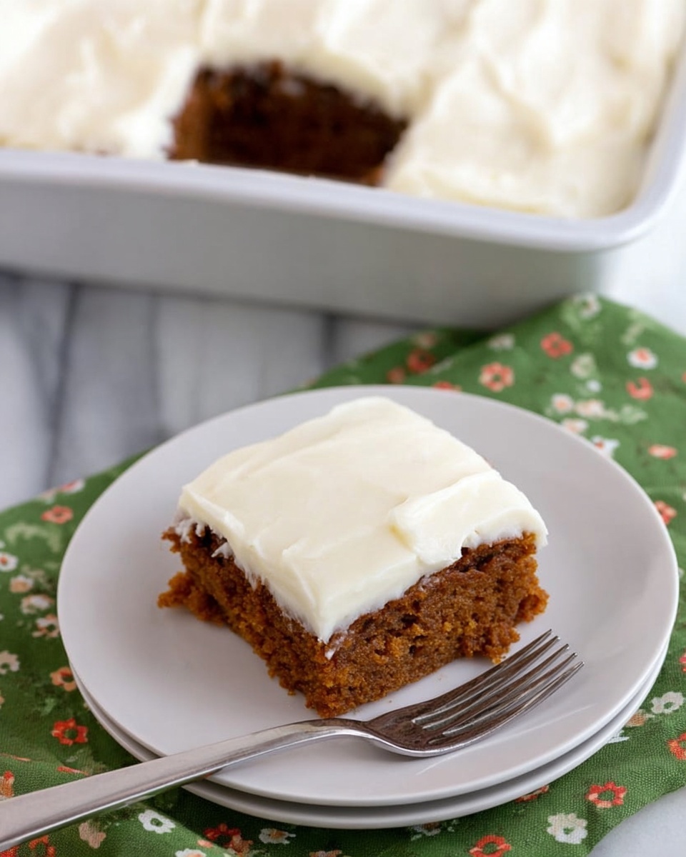 A square piece of carrot cake with two layers is shown on a white plate. The bottom layer is moist and orange-brown with a coarse texture. The top layer is smooth white cream cheese frosting, spread thickly and evenly. Behind the plate is a baking pan with more cake, with one piece missing from the corner. The scene is set on a wooden surface with a green napkin with white and red floral patterns beside the plate. A silver fork rests next to the cake piece on the plate. Photo taken with an iphone --ar 4:5 --v 7