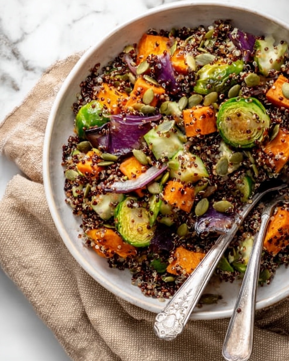 A clear glass bowl sits on a white marbled surface, filled with a colorful fall quinoa salad. The salad has about four layers of ingredients: bright orange roasted squash chunks, dark green leafy spinach, small pieces of light green cucumber, and purple onions with some green broccoli florets. The quinoa is mixed throughout the salad, visible as small brown grains. A white cloth napkin is on the right side, near a small jar with yellow dressing inside. The bowl is partly covered with a red lid that has a white label reading
