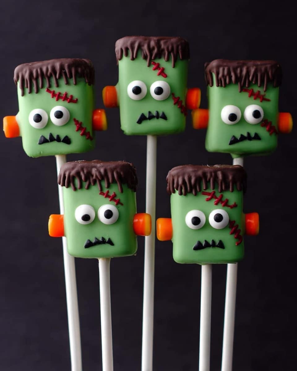 The image shows seven marshmallow pops designed like little Frankenstein heads placed on white sticks. Each marshmallow is covered in smooth green icing forming the face, with round white candy eyes topped with small black pupils positioned near the top center. The mouth is drawn with a simple black zigzag line resembling stitches. Above the eyes, there is brown icing on the top resembling messy hair that drips down slightly unevenly, covering the top third of each marshmallow. On one side of each marshmallow, there is a small, round orange candy or pretzel stick acting as Frankenstein's bolts or ears. The background is plain black, and the pops are arranged standing close together in a slight arc. Photo taken with an iphone --ar 4:5 --v 7