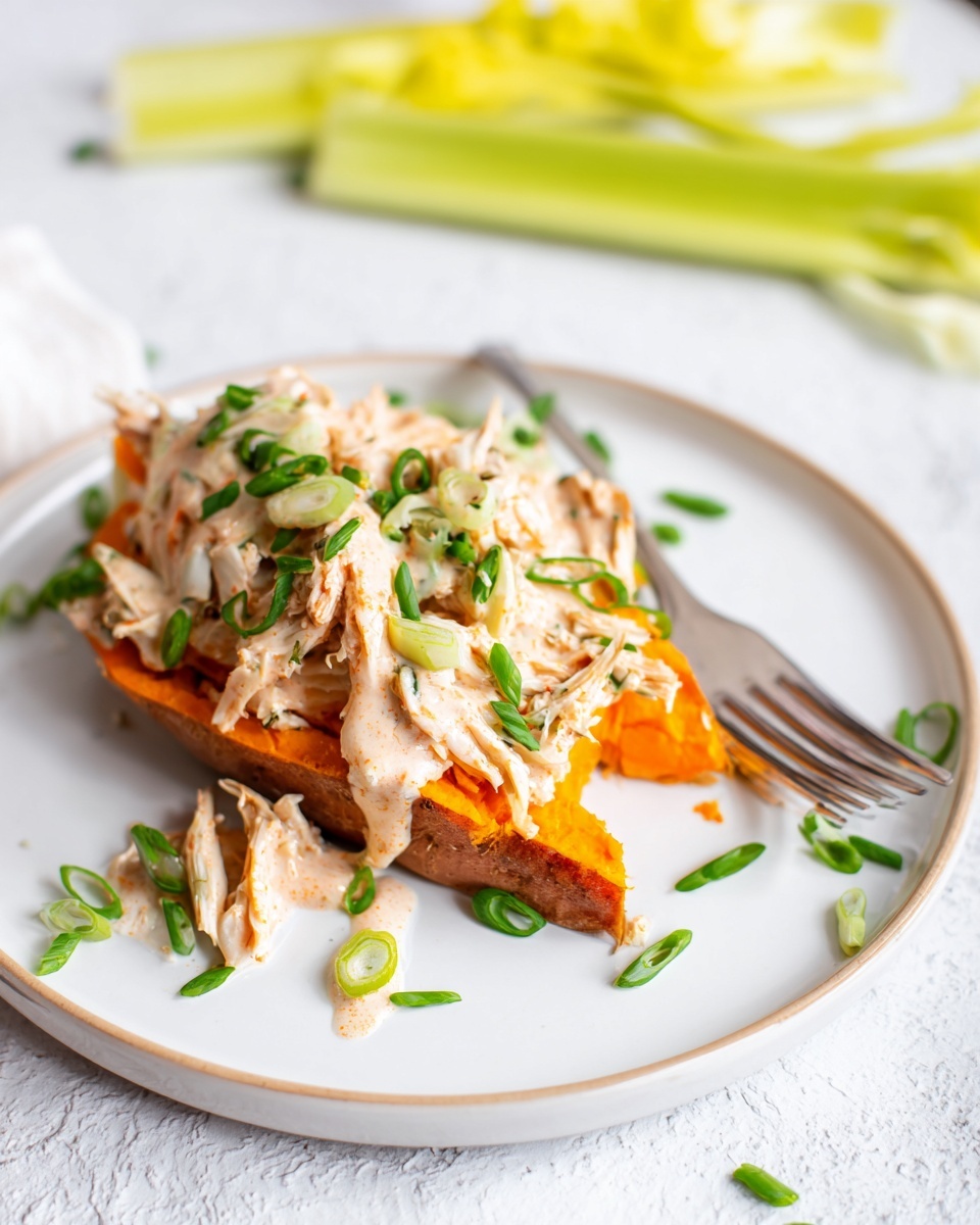 The dish shows one thick orange layer of roasted sweet potato as the base on a white plate with a white marbled texture surface underneath. On top of the sweet potato, there is a layer of shredded light beige chicken mixed with light orange sauce draped unevenly, creating a textured look. Green chives are sprinkled on top and around the plate, adding small bright green details. To the side of the plate, there are light yellow celery stalks lying down, adding a fresh touch. The overall scene is bright and clean with a white fork resting on the edge of the plate. The photo taken with an iphone --ar 4:5 --v 7