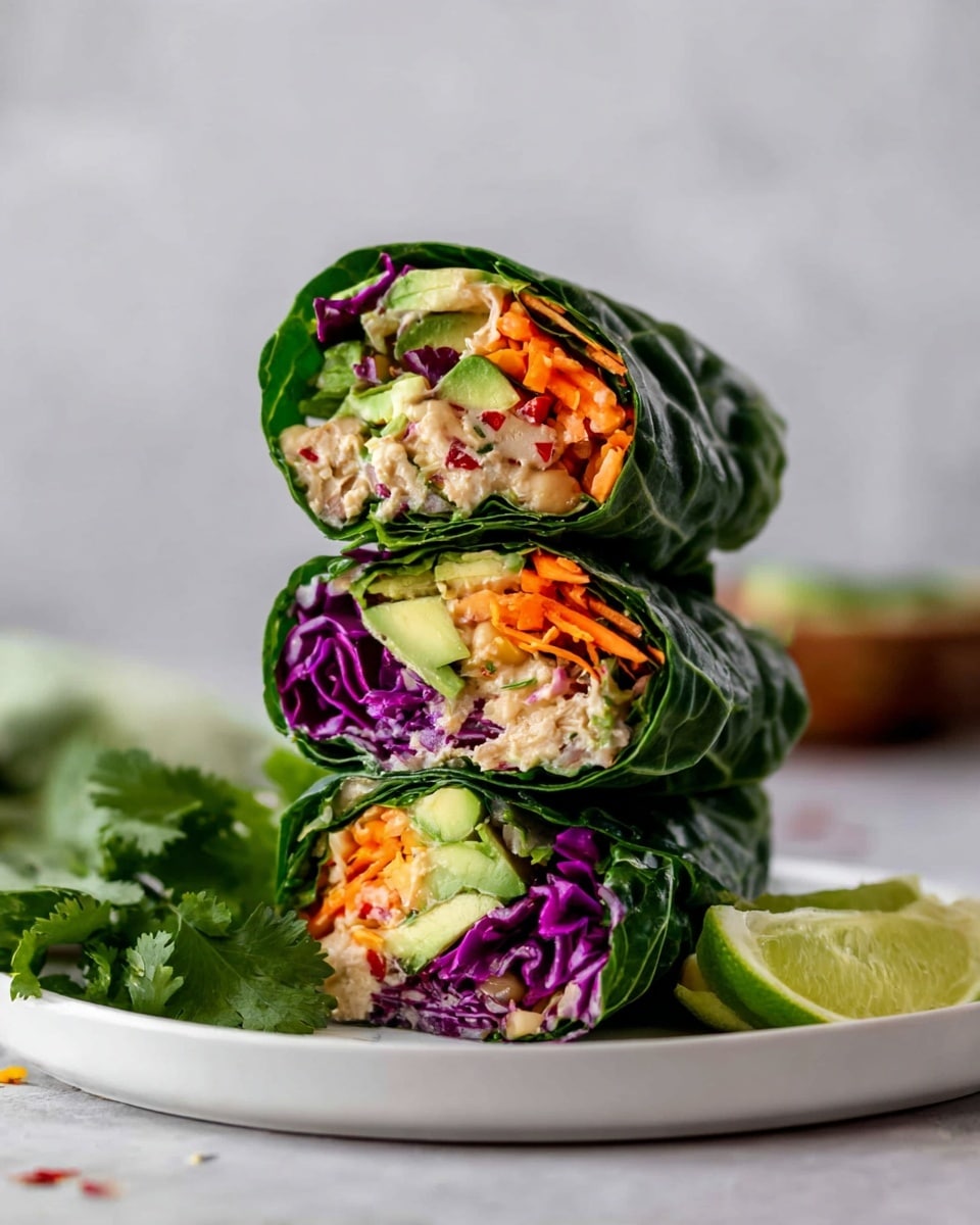 The image shows a stack of three fresh vegetable wraps, each wrapped in large dark green leafy lettuce. Inside each wrap, there are visible layers including bright orange shredded carrots, thin purple cabbage slices, chunks of green avocado, and a creamy beige filling that looks like a mix of tofu or beans with some small red pepper bits. The wraps are arranged vertically on a white plate with a few fresh cilantro leaves and lime wedges at the side. The background is a white marbled surface, with soft lighting highlighting the colors and textures of the fresh ingredients, and giving the image a fresh and healthy feel. Photo taken with an iphone --ar 4:5 --v 7
