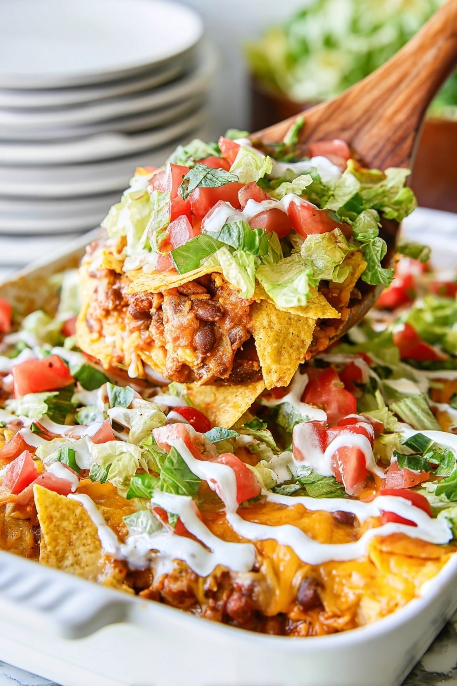 Creamy Chicken Taco Casserole Recipe 5 A white oval baking dish filled with a layered dish starting with a base layer of cooked pieces of chicken mixed with a red sauce, topped with a layer of crushed yellow tortilla chips. On top of this is a fresh layer of chopped green lettuce and diced red tomatoes. The dish is finished with white sour cream drizzled in diagonal lines across the top. The dish is placed on a surface with a white marbled texture. photo taken with an iphone --ar 4:5 --v 7