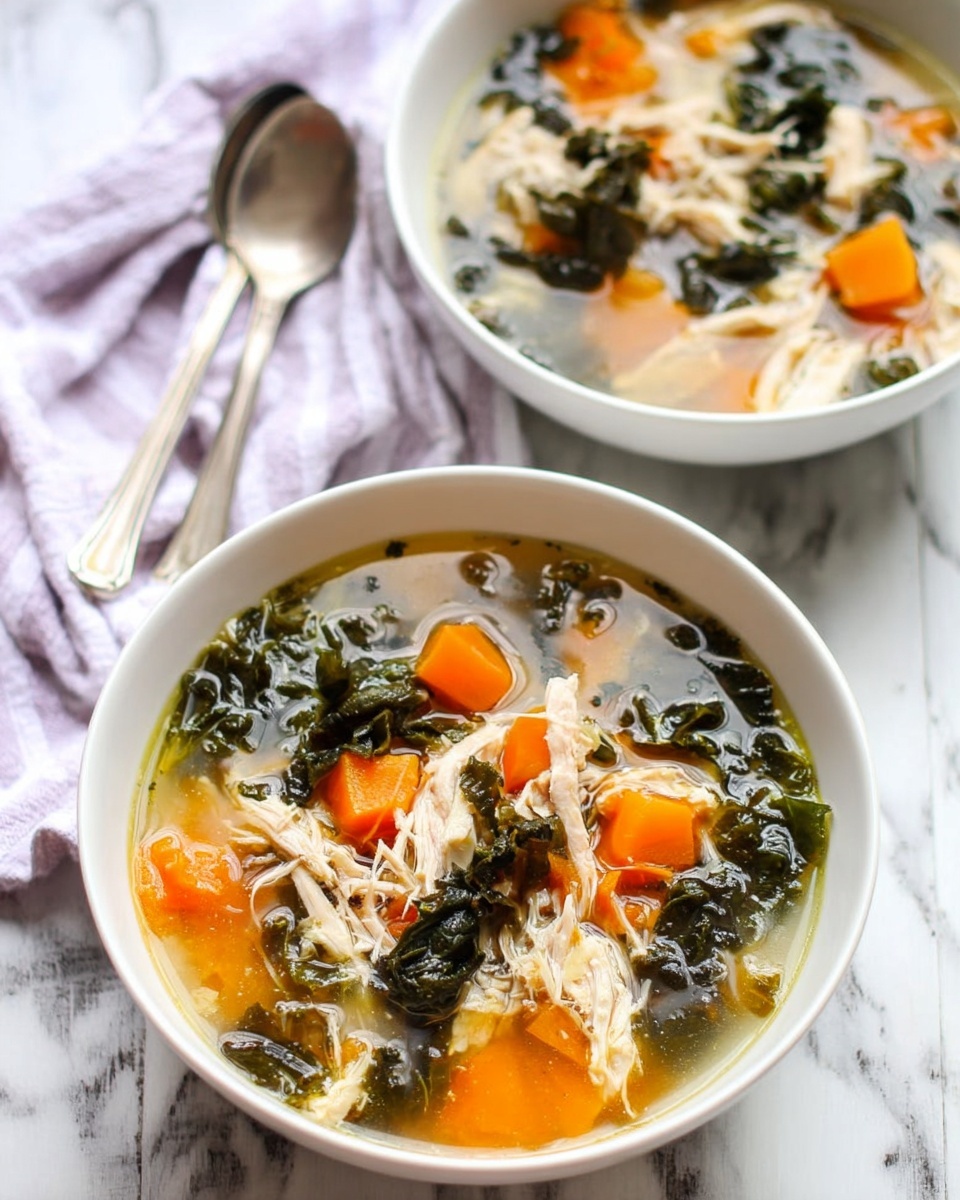 Two white bowls filled with soup sit on a white marbled surface. Each bowl has a clear broth with dark green leafy vegetables floating in it, along with bright orange chunks that look soft. There are also pieces of white shredded meat spread evenly throughout. Near the bowls, two tarnished silver spoons rest side by side. A soft purple and white striped cloth is visible in the background. photo taken with an iphone --ar 4:5 --v 7