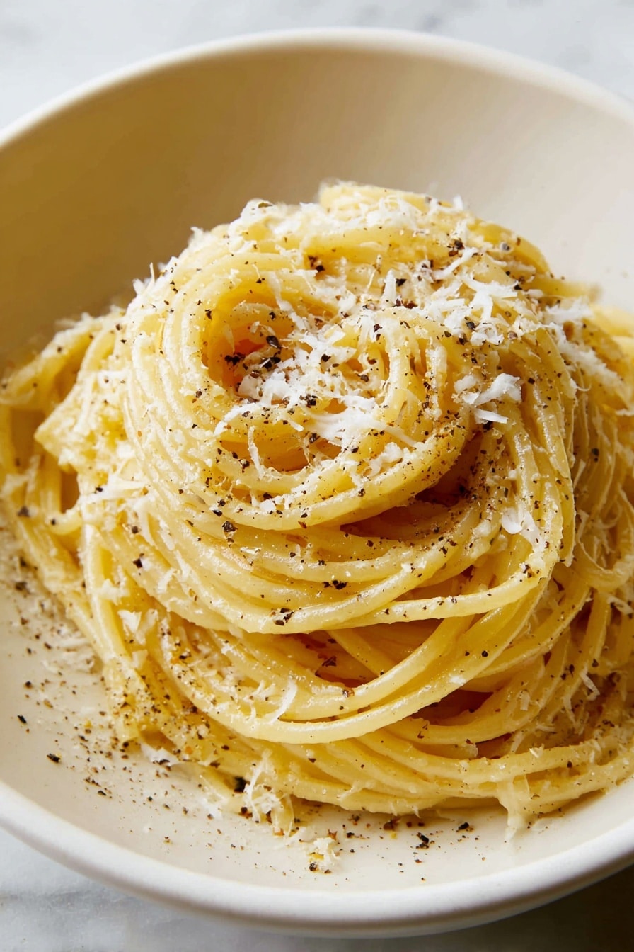 A white rustic bowl holds a tall pile of yellow spaghetti pasta, lightly coated with oil and speckled with black pepper. Soft, fine white cheese shavings are scattered over the spaghetti, adding a slight snowy texture on top. A silver fork, held by a woman's hand, lifts a twist of spaghetti strands from the heap, showing the noodles’ smooth, shiny surface. In the background, slightly blurred, is a white bowl with more grated cheese on a white marbled surface with a beige cloth nearby. Photo taken with an iphone --ar 4:5 --v 7