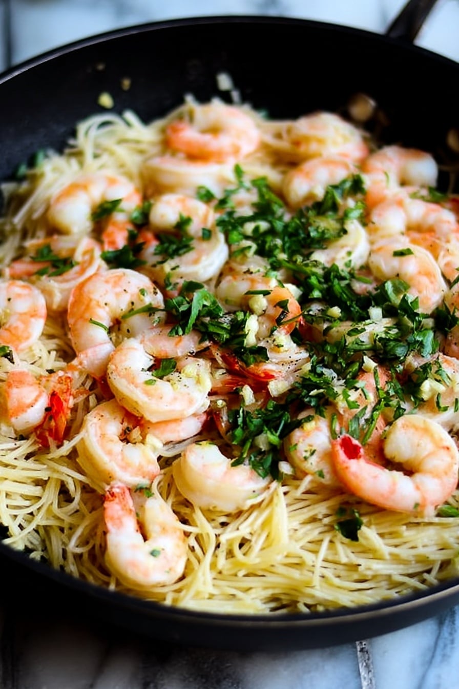 The dish shows a dark pan filled with thin yellow noodles layered underneath bright pink cooked shrimp placed evenly on top, with small green chopped herbs sprinkled all over. The noodles look soft and slightly shiny, mixed with some small pieces of white garlic visible on the edges. The shrimp are curled and firm, adding a splash of color and texture contrast to the smooth noodles below. The background is a white marbled surface that highlights the colors in the pan photo taken with an iphone --ar 4:5 --v 7