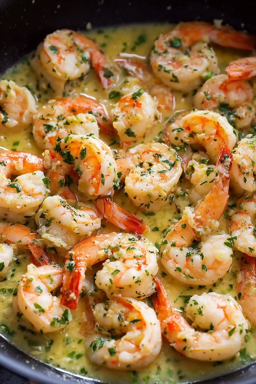 The image shows a close-up of many cooked shrimp in a white pan, arranged closely together in one layer. Each shrimp is pinkish-orange with white highlights, showing their cooked texture, and they are covered with small bits of green herbs and a light yellow sauce that looks oily and creamy. The shrimp have their tails still on, curling naturally. The sauce fills the spaces between the shrimp, adding shine and a soft texture. The background is a white marbled surface. Photo taken with an iphone --ar 4:5 --v 7