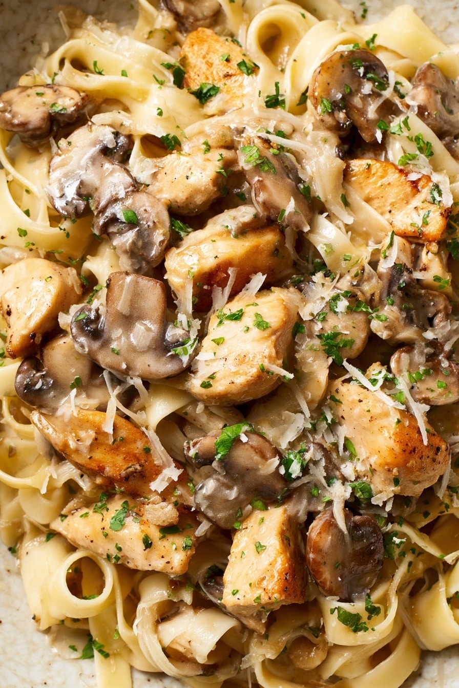 Creamy Chicken Marsala Pasta Recipe 5 The image shows a close-up of a creamy pasta dish with wide, flat noodles forming the base layer, light beige in color with a soft, smooth texture. On top, there are golden brown chunks of cooked chicken scattered throughout, mixed with thick, sliced brown mushrooms. The creamy sauce lightly coats the noodles and ingredients, giving a shiny, smooth finish. Small bits of green parsley are sprinkled over the whole dish, adding a touch of color. Some finely grated cheese is scattered around, melting slightly into the sauce. The dish is set against a white marbled surface. photo taken with an iphone --ar 4:5 --v 7