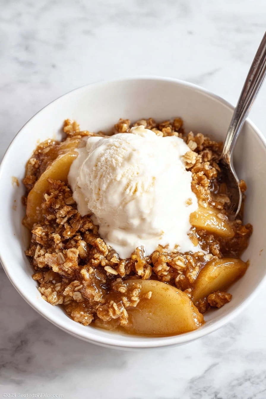Easy Apple Crisp Recipe with Oat Topping Recipe 6 A white bowl filled with a warm dessert showing two main layers: the bottom layer is soft, sliced fruit in a shiny, caramel-colored sauce, and the top layer is a crumbly, golden-brown oat topping with a rough texture. The dish looks moist and sticky, with the sauce blending smoothly around the fruit and oats. The bowl sits on a white marbled surface. photo taken with an iphone --ar 4:5 --v 7