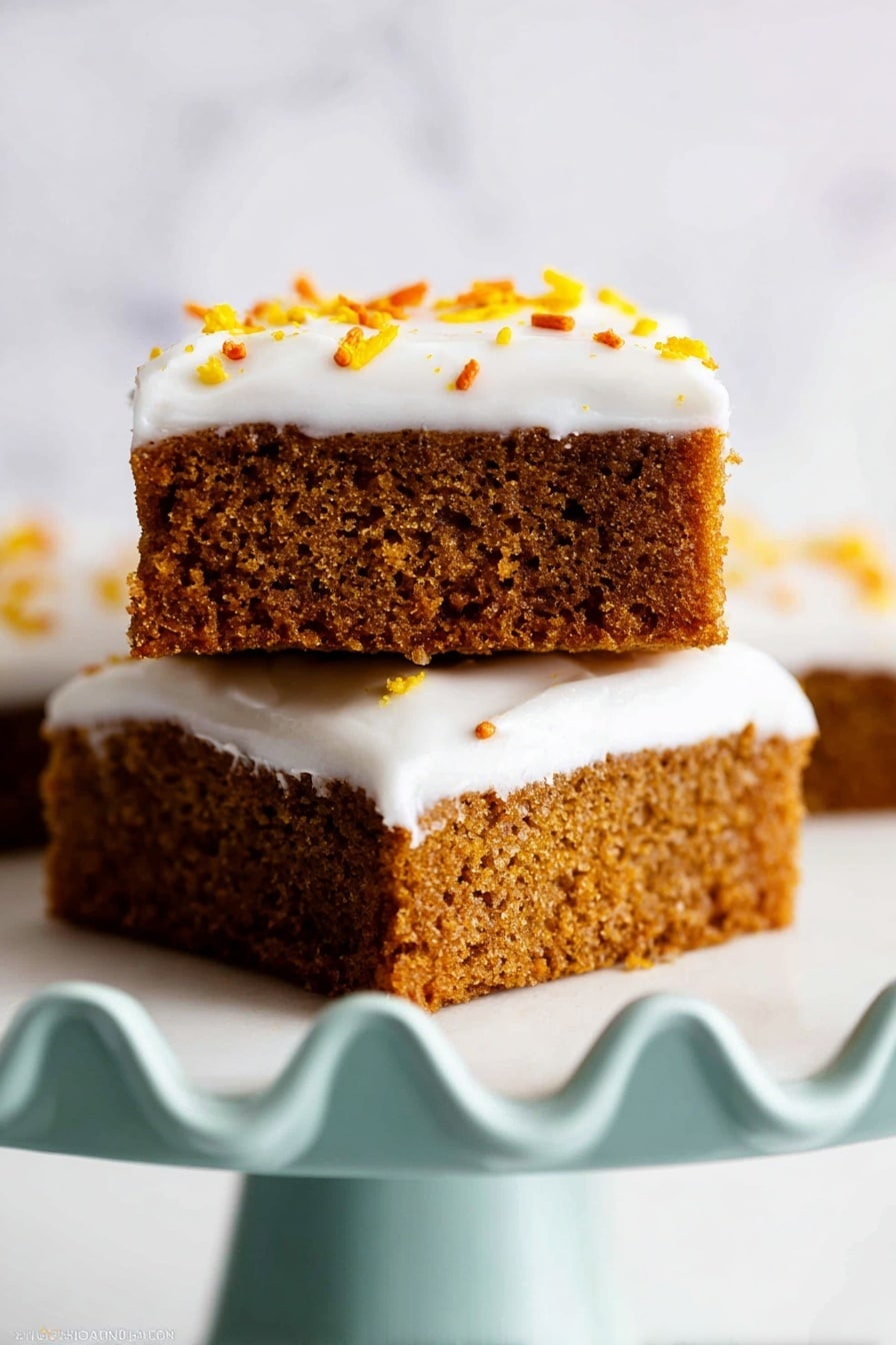Two square pieces of brown cake with small holes stacked on a white marbled surface. The bottom cake layer is dense with a textured surface, topped by a thin layer of smooth white frosting. The top cake piece has a thick layer of white frosting with small orange and yellow sprinkles on top. The cakes sit on a white plate with a scalloped edge, and the background is a plain white marbled texture. photo taken with an iphone --ar 4:5 --v 7