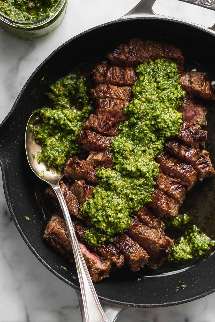 A black pan with a handle is filled with sliced cooked steak arranged in a single layer, showing a dark brown grilled outside with a slightly pink inside. On top, there is a thick layer of bright green pesto sauce spread unevenly, with some sauce spilling around the edges of the meat. A spoon with some pesto rests inside the pan on the left side. The pan is placed on a white marbled surface, and there is a small jar of pesto visible in the upper left corner. photo taken with an iphone --ar 4:5 --v 7