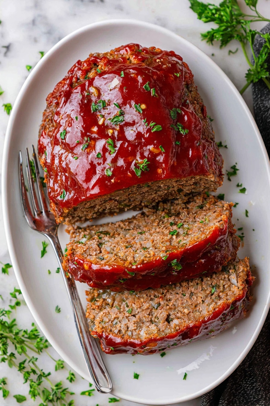 Easy Classic Meatloaf with Tangy Glaze Recipe 5 A white plate holds a serving of mashed potatoes on the left side, creamy and pale yellow with melted butter on top and small green parsley flakes sprinkled over it. Next to the mashed potatoes, there are two thick slices of meatloaf, with a textured brown inside and a shiny red tomato sauce layer on top, also sprinkled with small green herbs. On the upper part of the plate, there are green beans, long and bright green, arranged neatly behind the meatloaf. The whole scene is set on a white marbled surface, and a fork is visible in the upper right corner. photo taken with an iphone --ar 4:5 --v 7