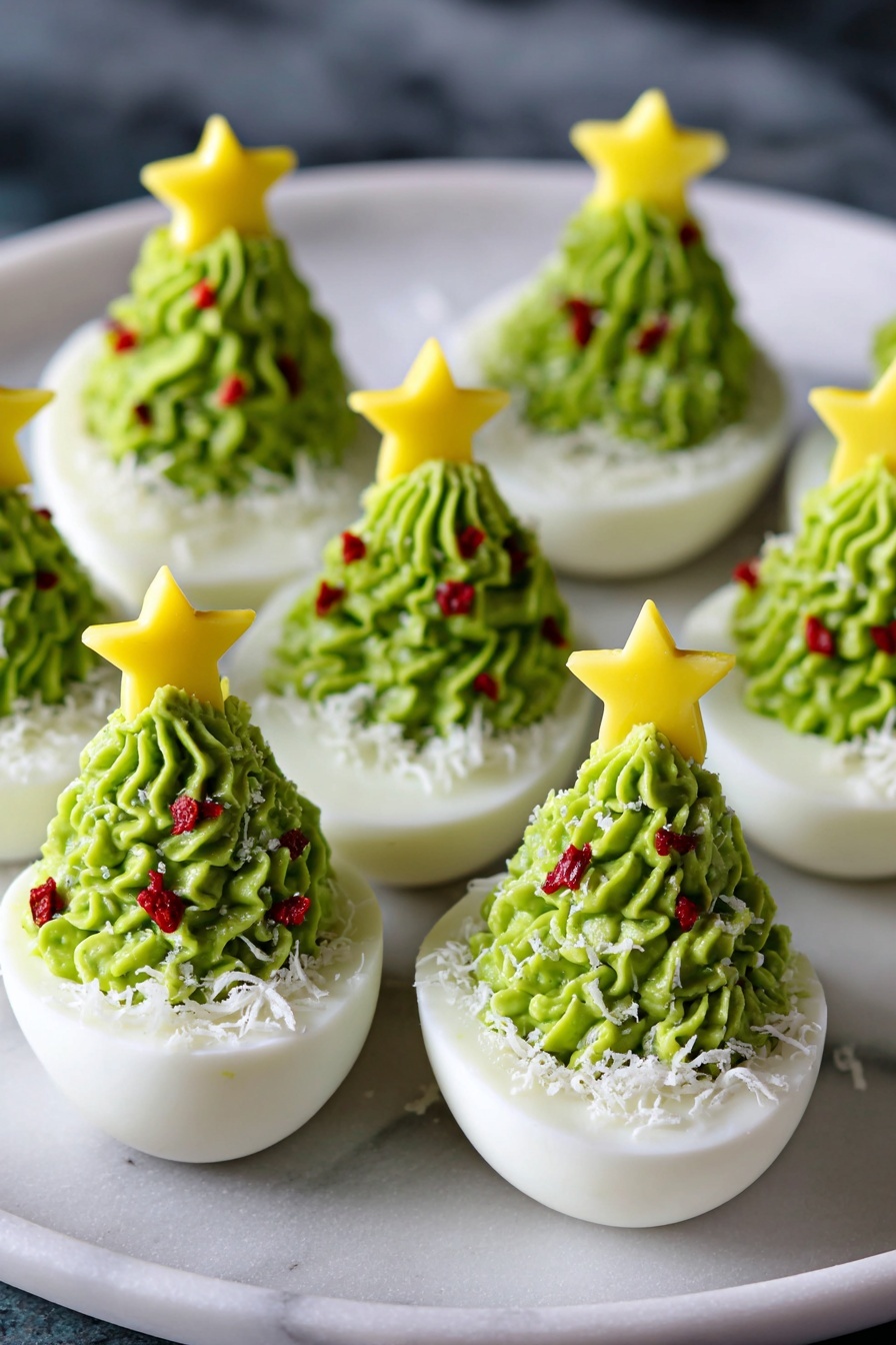 The image shows several white half boiled eggs arranged on a round black plate placed on a white marbled surface. Each egg half is topped with a green creamy layer swirled to look like a Christmas tree, decorated with small red bits scattered around to mimic ornaments. The green layer has a soft, smooth texture with white shredded pieces sprinkled over it to resemble snow. At the top of each green swirl is a small yellow star-shaped piece adding a festive touch. The eggs are closely placed, with their creamy green tops standing tall and textured, creating a festive and colorful holiday look. Photo taken with an iphone --ar 4:5 --v 7