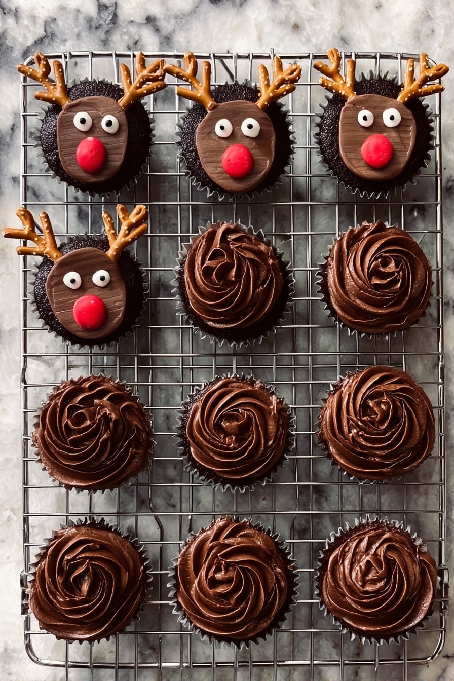 Rudolph Cupcakes with Chocolate and Candy Recipe 6 A metal cooling rack holds twelve chocolate cupcakes on a white marbled surface. Seven cupcakes are decorated as reindeer with a smooth, dark chocolate frosting base, topped with a rectangular chocolate piece for the face, two round white candy eyes, a small round red candy nose, and two small pretzel pieces shaped like antlers, placed near the top edges. The other five cupcakes have swirled dark chocolate frosting, with a textured, soft and creamy look, forming a rose-like pattern on top. Photo taken with an iphone --ar 2:3 --v 7 - Rudolph Cupcakes with Chocolate and Candy, festive Christmas cupcakes, holiday reindeer cupcakes, easy holiday cupcake ideas, cute Rudolph dessert