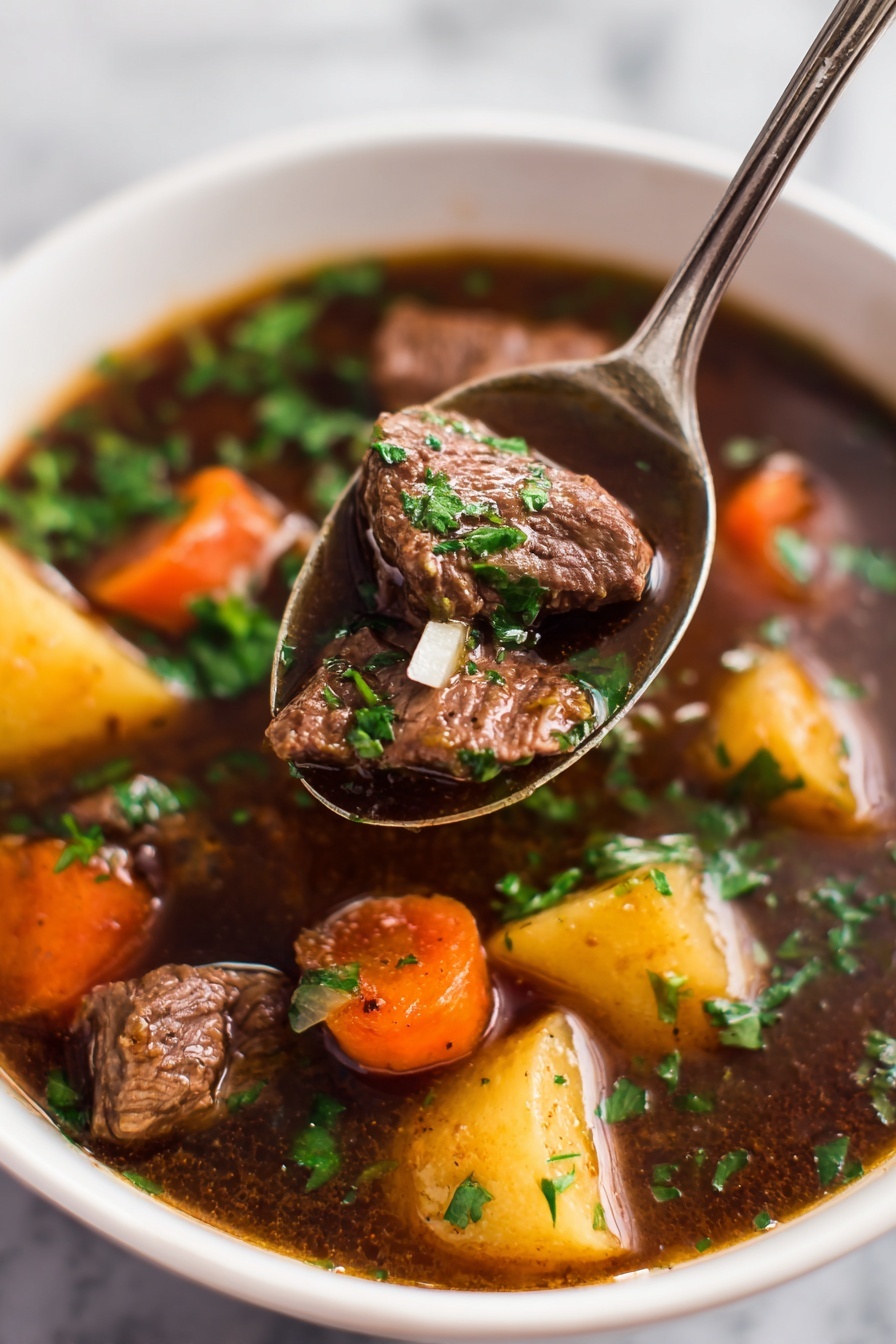 Slow Cooker Beef Stew Recipe 8 A white bowl filled with a thick beef stew showing three main layers: at the bottom, light brown potato chunks with a soft texture; the middle layer has bright orange carrot pieces that look tender; and the top layer consists of dark brown beef chunks coated in rich brown gravy with some small green herb sprinkles scattered on top. A silver spoon holds a chunk of beef above the bowl, with visible glossy gravy. The bowl rests on a white marbled surface. photo taken with an iphone --ar 2:3 --v 7 - Slow Cooker Beef Stew, easy beef stew, hearty slow cooker recipes, comforting beef stew, tender beef stew recipe