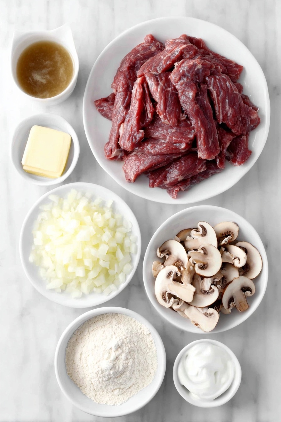Easy Beef Stroganoff Recipe 7 Flat lay of fresh thin strips of beef round arranged neatly on a simple white ceramic plate, a small mound of pale beige all-purpose flour on a white ceramic plate, a smooth pat of golden butter on a white ceramic dish, one medium onion finely diced in a small white ceramic bowl, a pile of thinly sliced brown mushrooms on a white ceramic plate, a small white ceramic bowl filled with rich brown beef broth, a small white ceramic bowl holding clear water, a pinch of fine salt arranged as a small pile on a white ceramic dish, a dollop of creamy white sour cream in a small white ceramic bowl placed symmetrically -- all ingredients looking fresh and natural, placed on a clean white marble surface, soft natural light, photo taken with an iPhone, professional food photography style, fresh ingredients, white ceramic bowls, no bottles, no duplicates, no utensils, no packaging --ar 2:3 --v 7 --p m7354615311229779997 - Easy Beef Stroganoff, beef stroganoff recipe, quick beef stroganoff, creamy beef dinner, hearty beef recipes