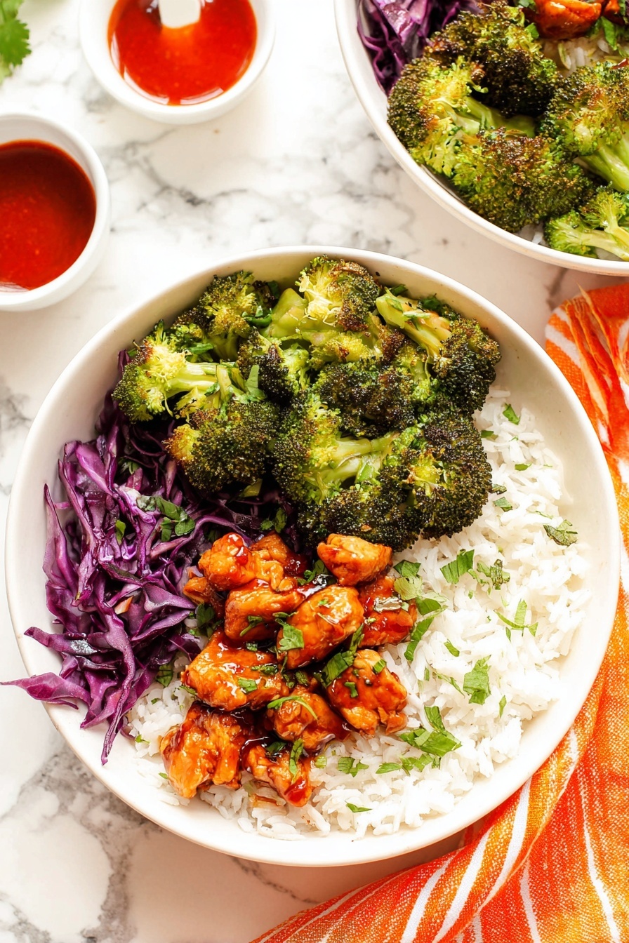 Hot Honey Chicken Bowl Recipe 8 The image shows a white bowl with three clear layers: the bottom layer is white rice with a soft texture, the middle layer on one side is bright green broccoli with a slightly rough texture, and the other side has shredded purple cabbage with a crisp look. On top, there are chunks of orange-red cooked chicken with a shiny glaze, scattered with small green herb pieces, giving a fresh look. In the background, another similar bowl is slightly out of focus, placed on a white marbled surface with a small white cup partially visible on the left side. photo taken with an iphone --ar 2:3 --v 7 - Hot Honey Chicken Bowl, flavorful chicken bowl, spicy honey chicken, easy healthy chicken dinner, sweet and spicy chicken bowl