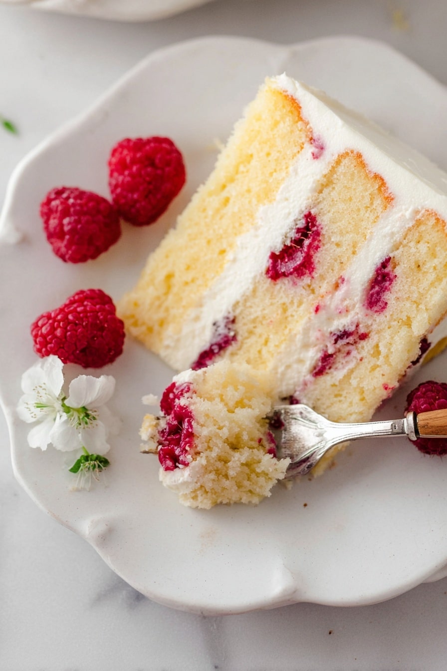 Lemon Raspberry Cake with Cream Cheese Frosting Recipe 8 A slice of yellow cake with three layers is shown on a white plate with scalloped edges, placed on a white marbled surface. The cake has bright red raspberries embedded inside the moist layers, separated by smooth white cream layers. A silver fork with a wooden handle holds a bite of the cake, revealing the soft texture and raspberry pieces in the bite. Three fresh raspberries and a small white flower are placed near the cake slice on the plate. The photo taken with an iphone --ar 2:3 --v 7 - Lemon Raspberry Cake with Cream Cheese Frosting, Lemon Raspberry Cake, Raspberry Layer Cake, Lemon Dessert Recipe, Cream Cheese Frosting Cake