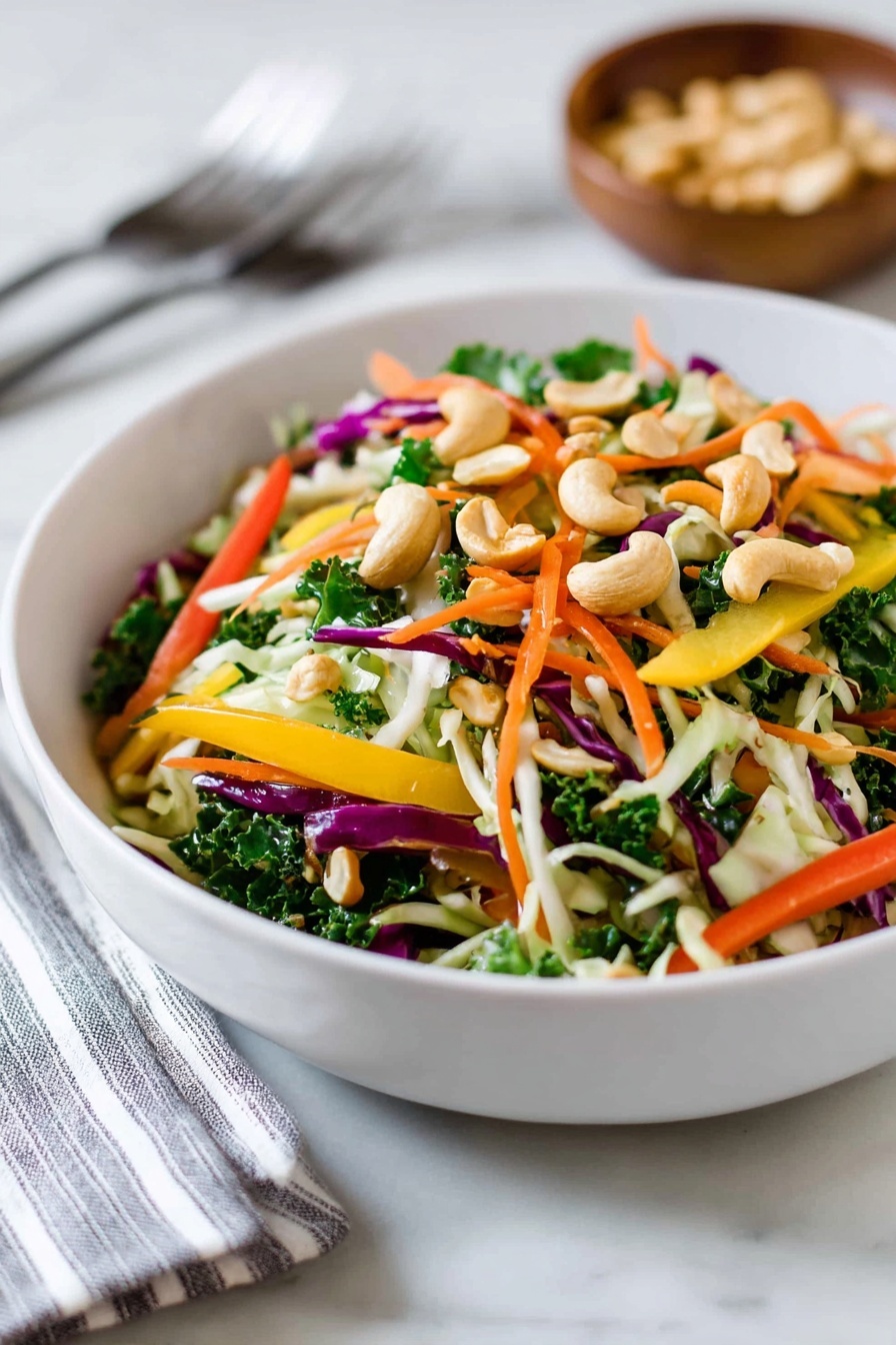 Asian Cashew Crunch Salad Recipe 8 A large white bowl filled with a colorful salad showing many thin layers: shredded light green cabbage, dark green kale leaves, thin orange carrot strips, small cucumber slices, and thin strips of red and yellow bell peppers. On top, many cashew nuts add a light brown crunchy texture scattered unevenly. The salad looks fresh and mixed, sitting on a white marbled surface with three forks placed to the side near a striped cloth. photo taken with an iphone --ar 2:3 --v 7 - Asian Cashew Crunch Salad, crunchy vegetable salad with cashews, tangy Asian salad recipe, healthy seafood salad, easy Asian salad ideas