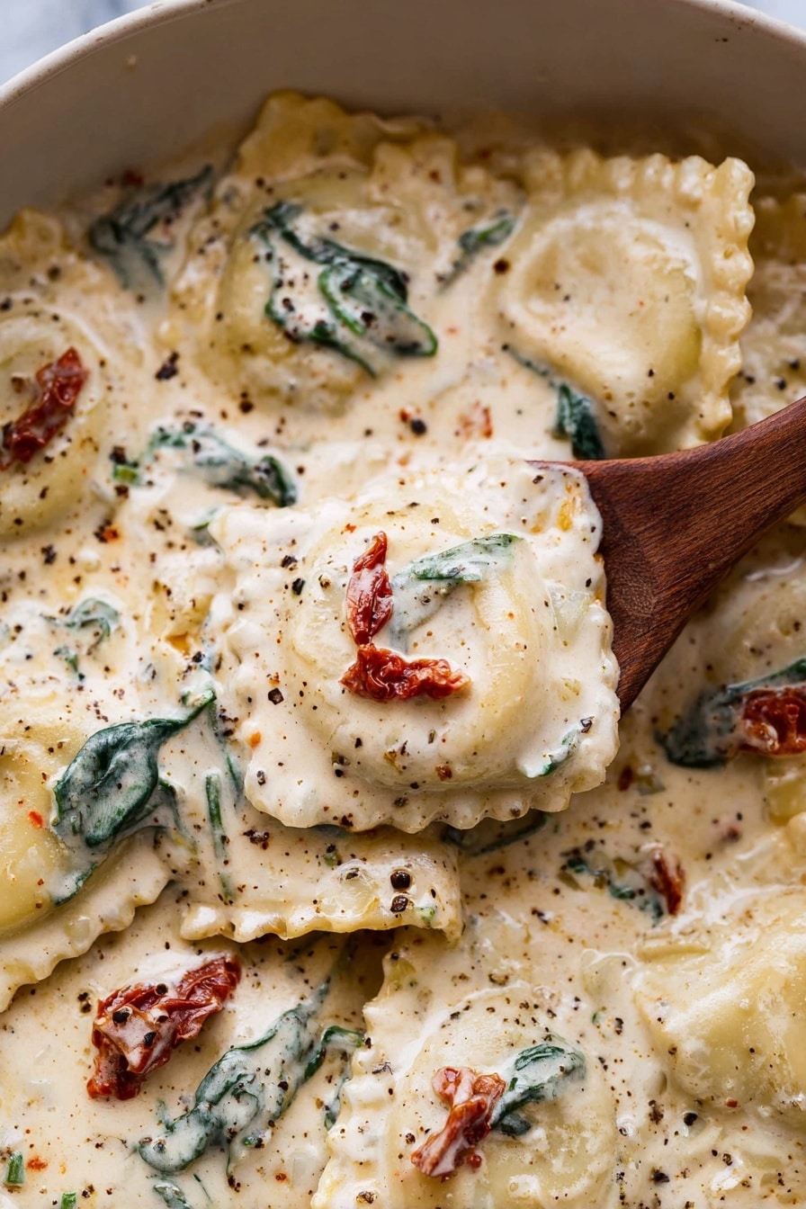 Creamy Tuscan Garlic Ravioli Recipe 6 A close-up of ravioli pasta in a creamy white sauce with visible specks of black pepper and herbs. The ravioli are square with ruffled edges, covered in a thick, smooth, off-white sauce that has a rich texture. Scattered throughout the sauce are dark green wilted spinach leaves and small pieces of red sun-dried tomatoes, adding color contrast. A wooden spoon is lifting one ravioli with the creamy sauce dripping slightly, showing the pasta's soft texture. The dish sits on a white marbled surface. Photo taken with an iphone --ar 2:3 --v 7 - Creamy Tuscan Garlic Ravioli, Tuscan garlic ravioli recipe, easy creamy ravioli dish, quick pasta dinner, garlic spinach sun-dried tomato pasta
