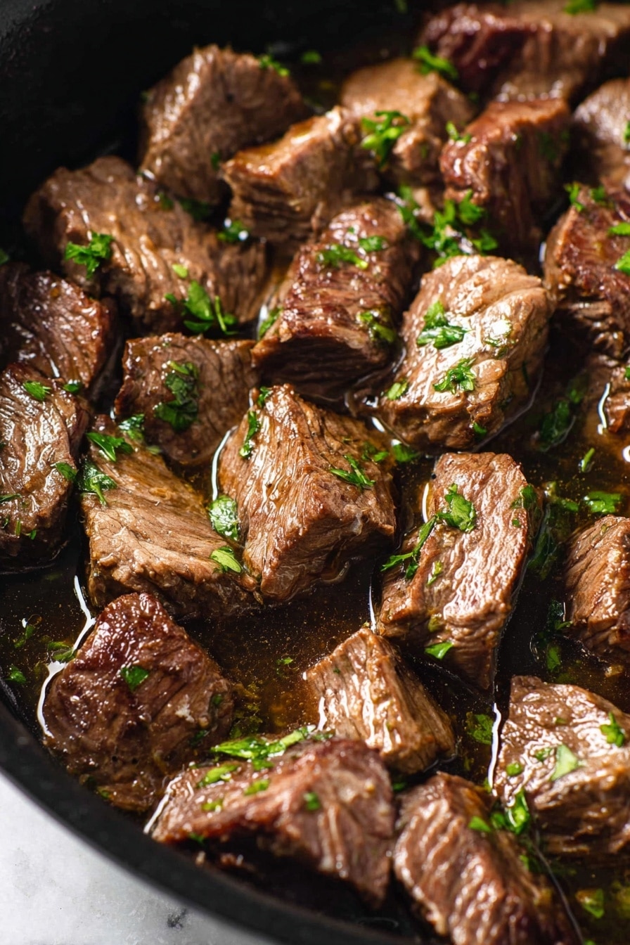 Mediterranean Steak Bites with Yogurt Sauce Recipe 8 This image shows a close-up of many pieces of cooked beef stew in a pan. Each beef piece is brown with slight darker grill marks and looks soft and juicy, sitting in a shiny broth. Small bits of bright green parsley are scattered evenly over the beef, adding a fresh touch. The pan is black and visible only around the edges, with the image set on a white marbled surface. The lighting makes the beef shine a little, showing its tender texture. photo taken with an iphone --ar 2:3 --v 7 - Mediterranean Steak Bites with Yogurt Sauce, Greek steak bites recipe, juicy steak appetizer with yogurt, quick Mediterranean steak snack, flavorful steak bites with sauce