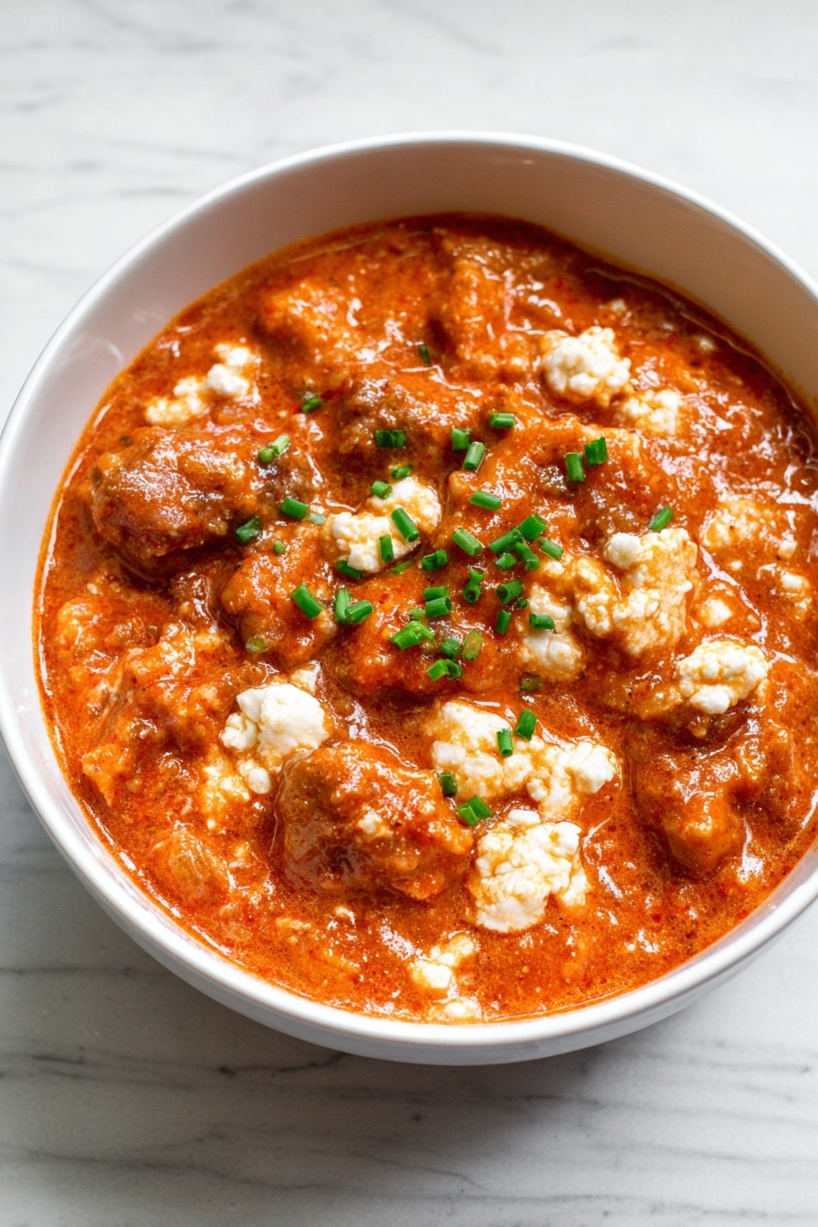 High-Protein Cottage Cheese Chicken Parm Bowl Recipe 6 The image shows a white bowl filled with a thick mix of orange-red sauce coating small white curd-like pieces and chopped green herbs. The sauce looks creamy and slightly chunky, with the white bits spread evenly through the mixture, making it look textured and rich. A gold spoon is partially visible on the right side, partly dipped into the bowl. The bowl sits on a white marbled surface. photo taken with an iphone --ar 2:3 --v 7 - High-Protein Cottage Cheese Chicken Parm Bowl, healthy chicken parmesan bowl, quick protein-packed dinner, low-carb cottage cheese chicken bowl, easy high-protein meal